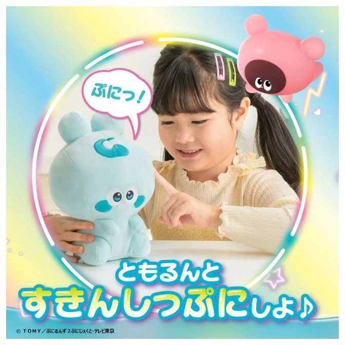  Girl playing with a blue plush toy and a pink toy. The blue toy has a cute face and a swirl on its head.