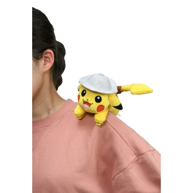 Pikachu plush toy wearing a white cap perched on a person's shoulder.
