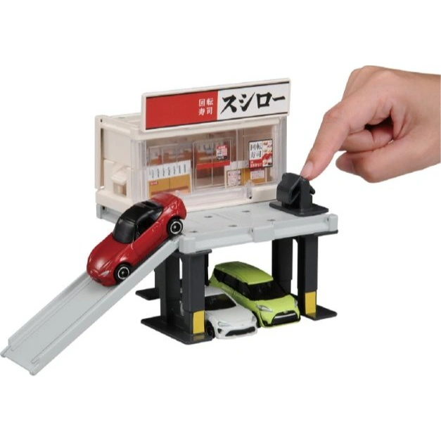  Toy car playset with sushi restaurant, ramp, parking. Hand presses button.