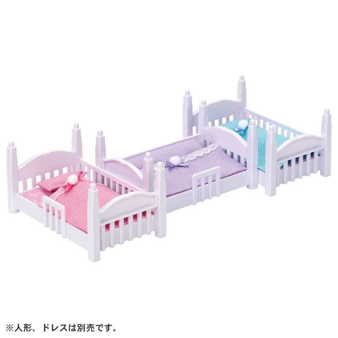  Three doll beds in pink, purple, and blue with white frames and bedding.