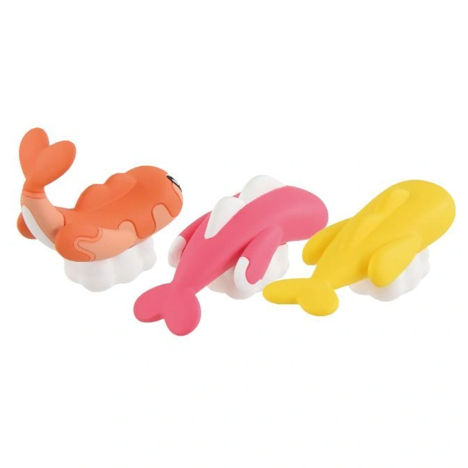  Three sushi-shaped toys: an orange shrimp and pink and yellow dolphins on white rice.