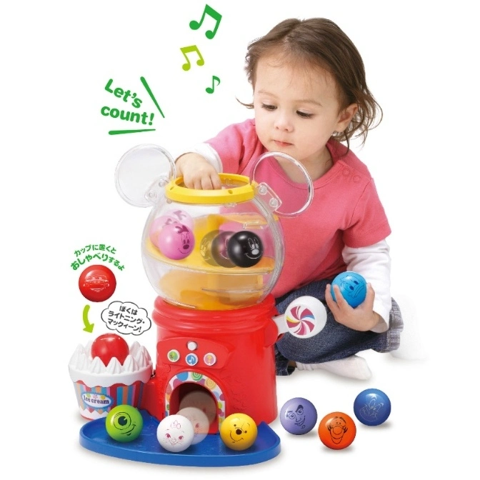  Child playing with a Mickey Mouse gumball machine toy with character-themed balls.
