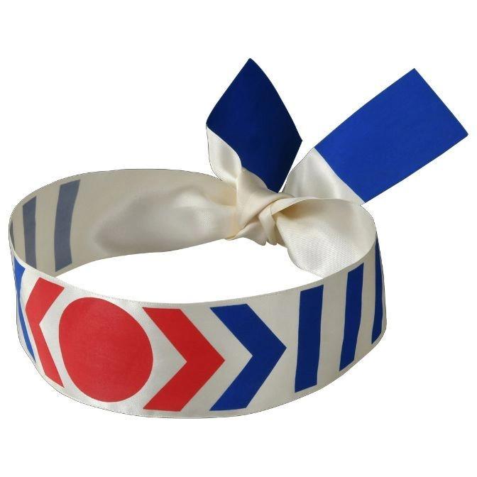  White hair tie with red circle, blue arrows, and stripes. Tied in a bow.