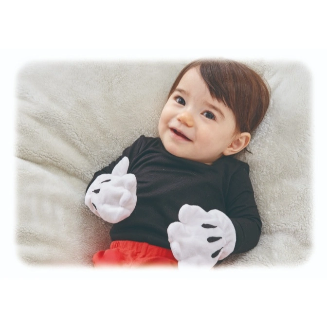  Baby in Mickey Mouse costume with gloves, lying on a soft blanket and smiling.