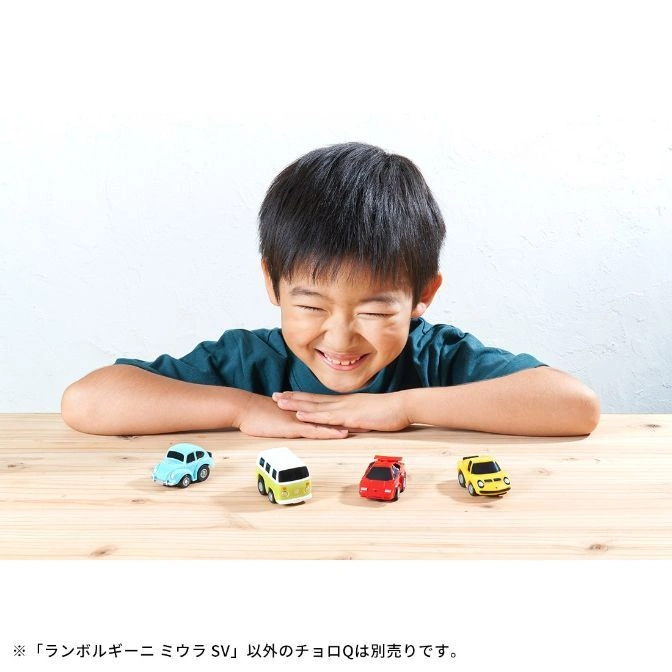  Smiling child with four toy cars: blue Beetle, white van, red sports car, yellow car.