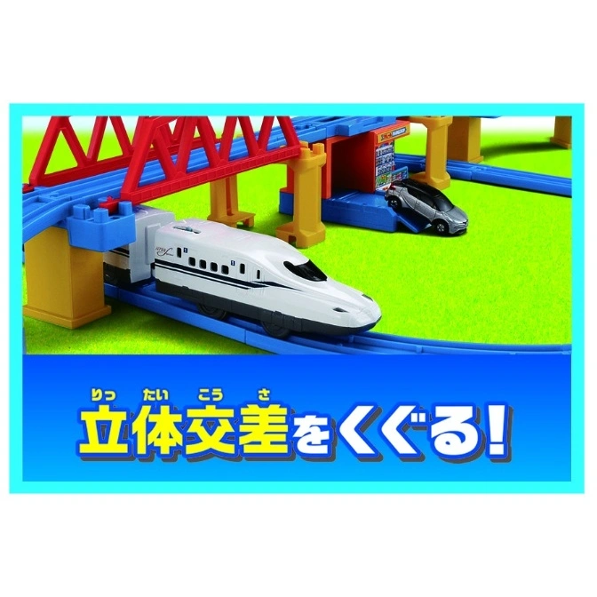  Toy train set with a bullet train passing under a bridge and a toy car parked nearby.