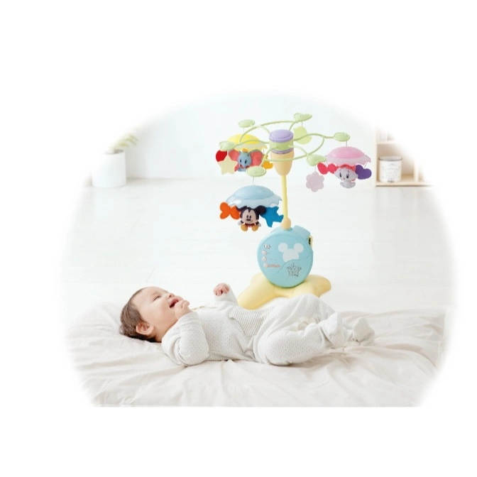 Baby lies under a Disney mobile with Mickey Mouse and Dumbo characters.