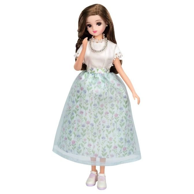  Doll with brown hair, wearing a floral skirt, white top, pearl necklace, and sneakers.