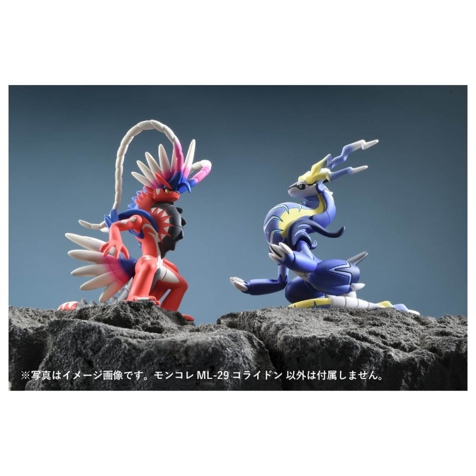 Koraidon and Miraidon Pokémon figures on a rocky surface, facing each other.