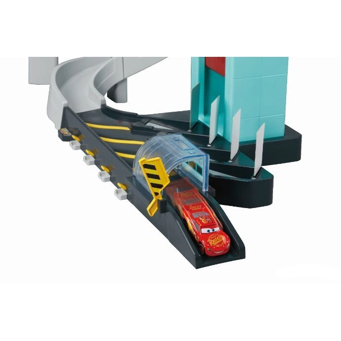  Cars playset with Lightning McQueen under a clear tunnel on a gray track with a blue building.