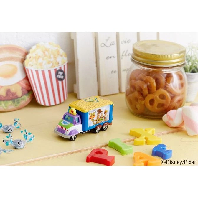  Toy Story truck with Woody and Buzz, surrounded by treats and colorful letter toys.