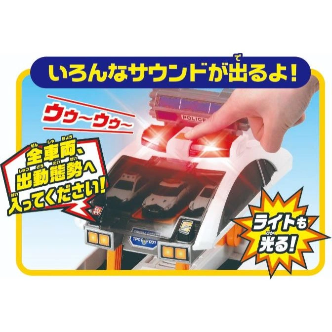 Toy police station with lights, sounds, and mini police cars. A hand presses a button.