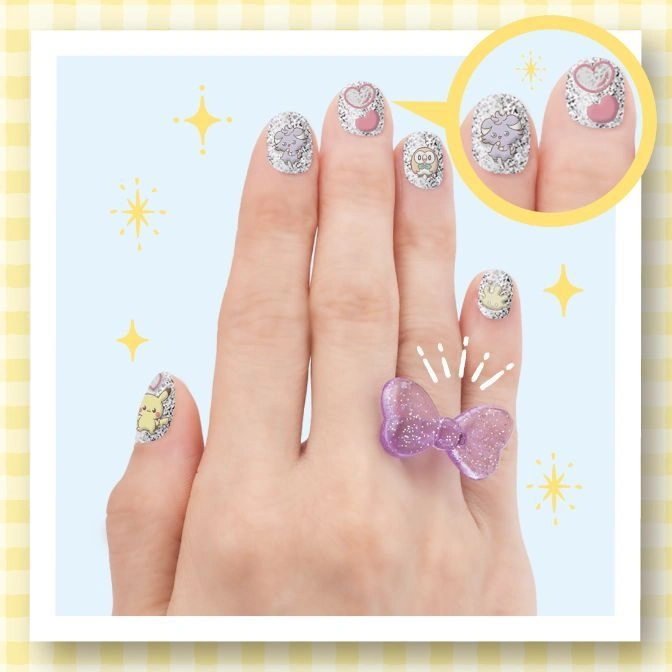  Hand with Pokémon nail art and a purple glitter bow ring.