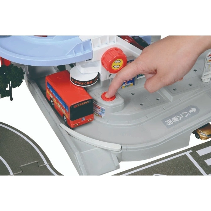  Toy bus station with a red bus, hand pressing a button, and a rotating knob.