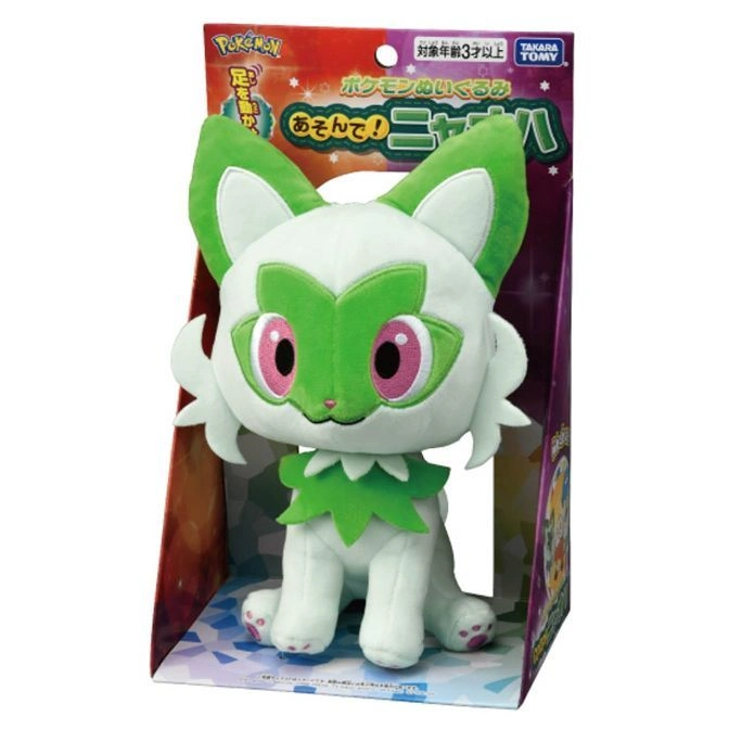 Sprigatito plush toy in box. White and green cat-like Pokémon with pink eyes.