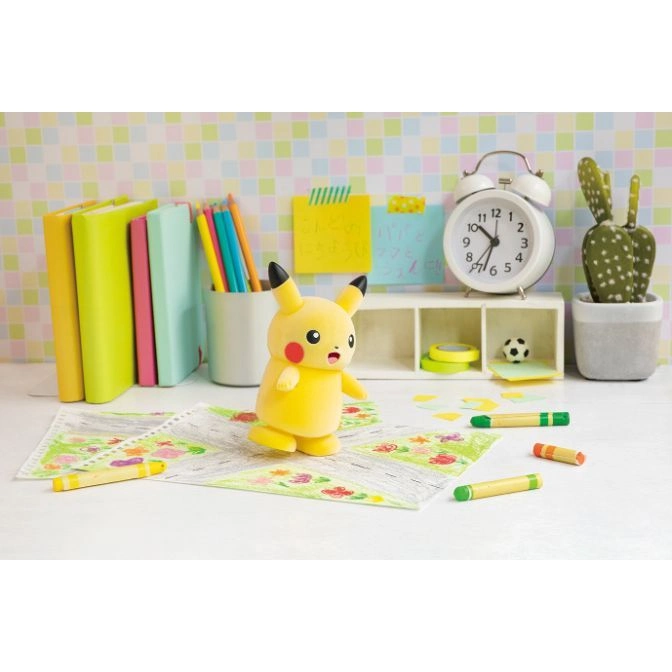  Pikachu toy on a desk with art supplies, books, and a clock.