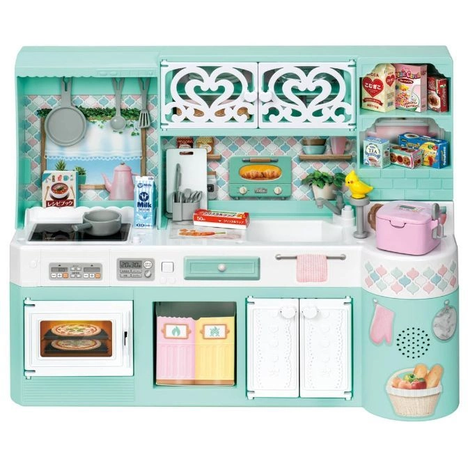 Mint green toy kitchen with oven, sink, cabinets, and accessories like food, cookware, and utensils.