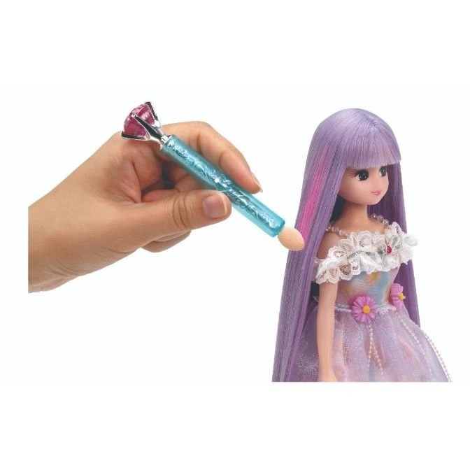  Doll with purple hair being styled with a gem-topped applicator.