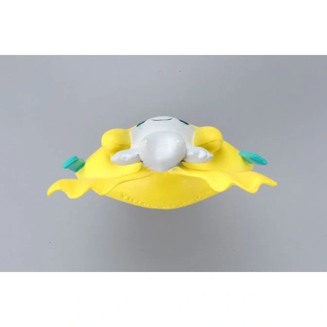 Yellow Comfey Pokémon toy with white face and green accents, viewed from above.