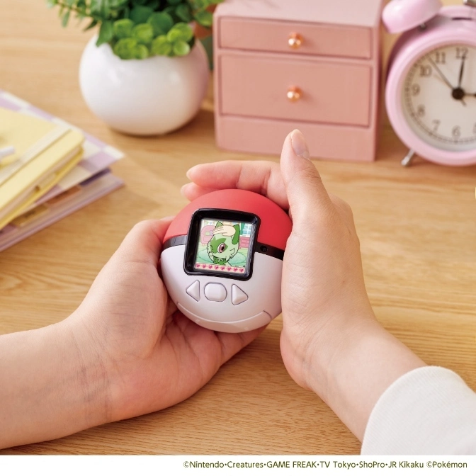 Pokémon Poké Ball virtual pet toy with screen showing a character, held in hands.