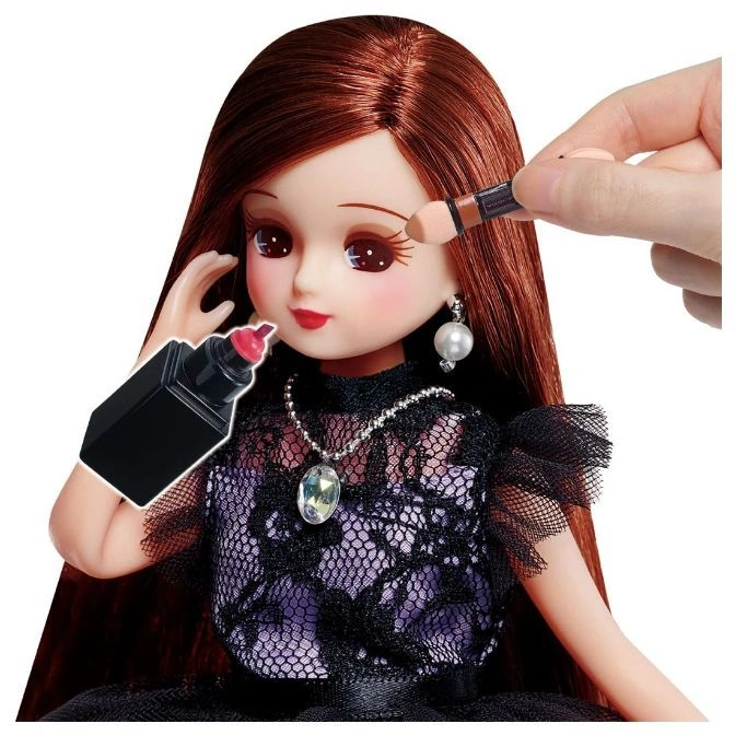 Doll with auburn hair getting makeup applied with a sponge applicator and marker.