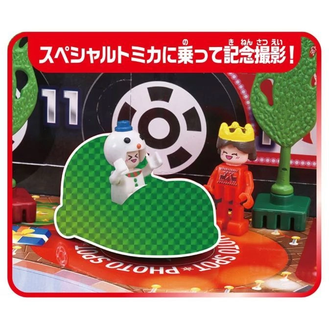  Toy playset with figures, including a snowman in a green car and a king, on a red and black stage.