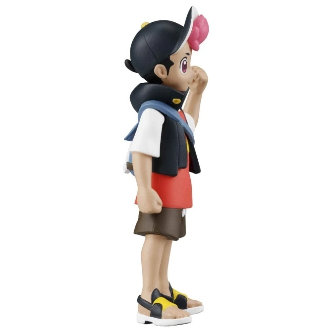  Pokémon figure of a boy with a cap, vest, shorts, and sandals, looking to the side.