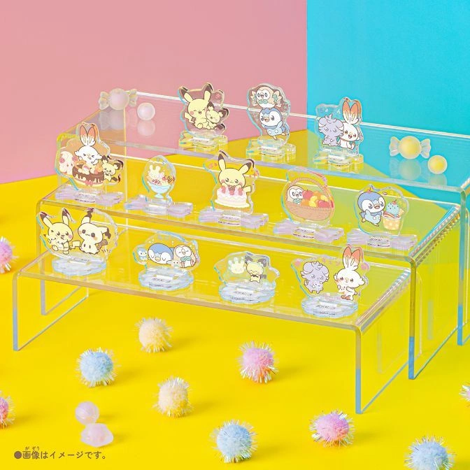  Pokémon character acrylic stands displayed on a tiered shelf with colorful pom-poms.