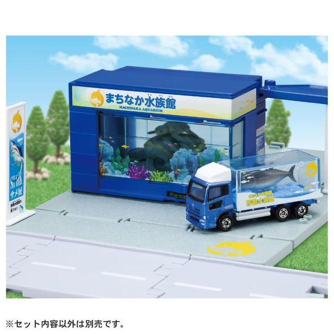 Toy aquarium with truck carrying a tuna. Miniature diorama with trees and road.
