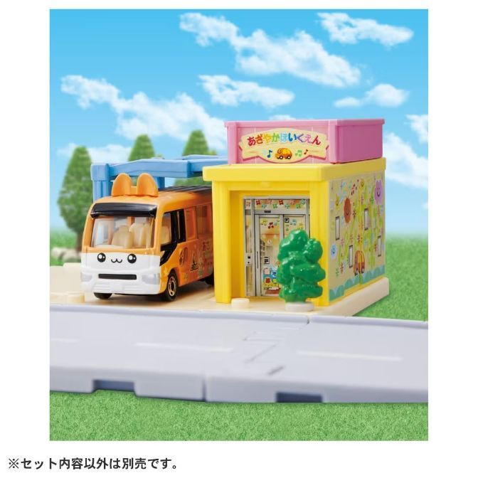 Toy bus at a playset with a building and road. The bus has bunny ears.