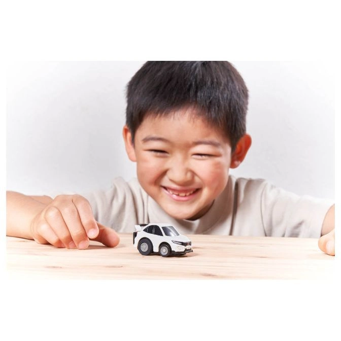  Smiling child plays with a white toy car on a wooden table.