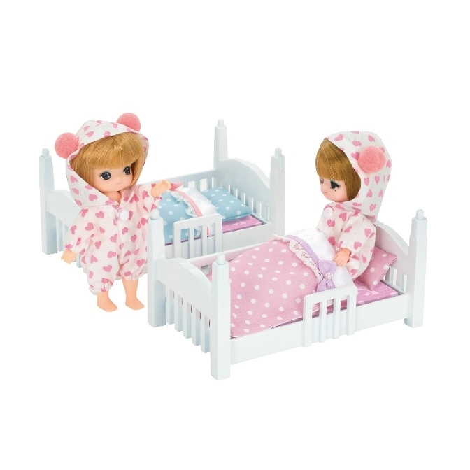  Two dolls in heart-patterned pajamas with toy beds. One doll is standing, the other is sitting in bed.