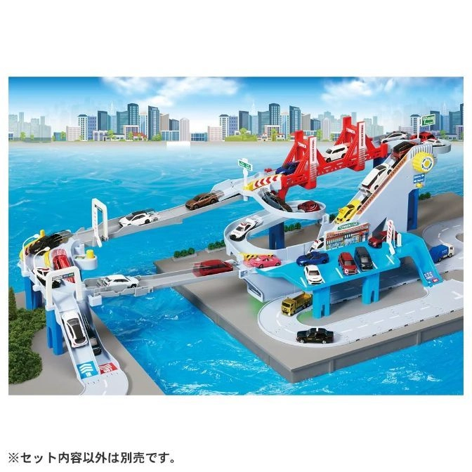  Toy car playset with ramps, bridges, and various toy vehicles on a cityscape backdrop.