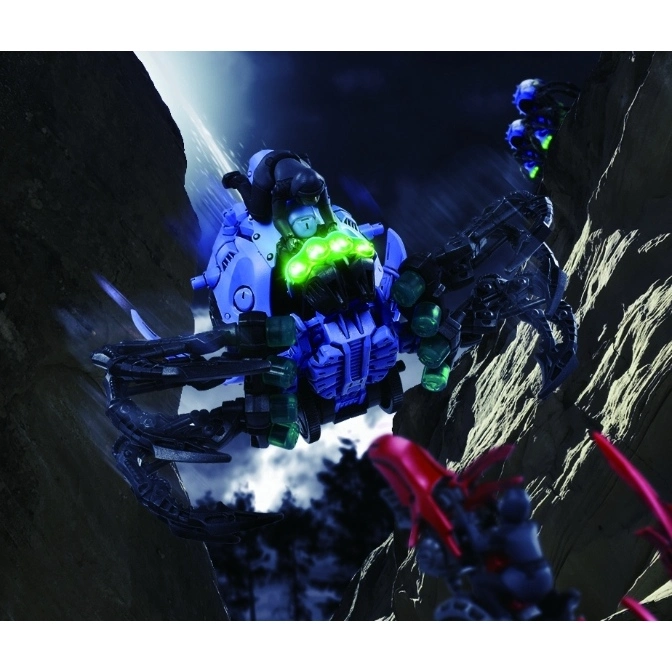  Blue scorpion robot toy with glowing green eyes and a rider, set in a rocky landscape.