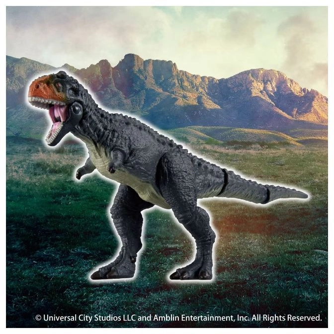  Grey dinosaur toy with orange head roaring in a field with mountains in the background.