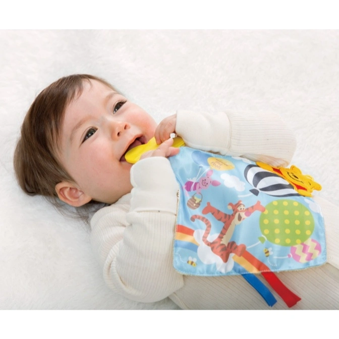  Baby chewing on a Winnie the Pooh-themed teething blanket with Tigger and balloon designs.