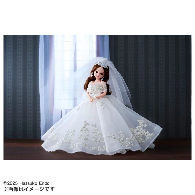  Doll in a white wedding gown with a veil and tiara, standing in front of a window.