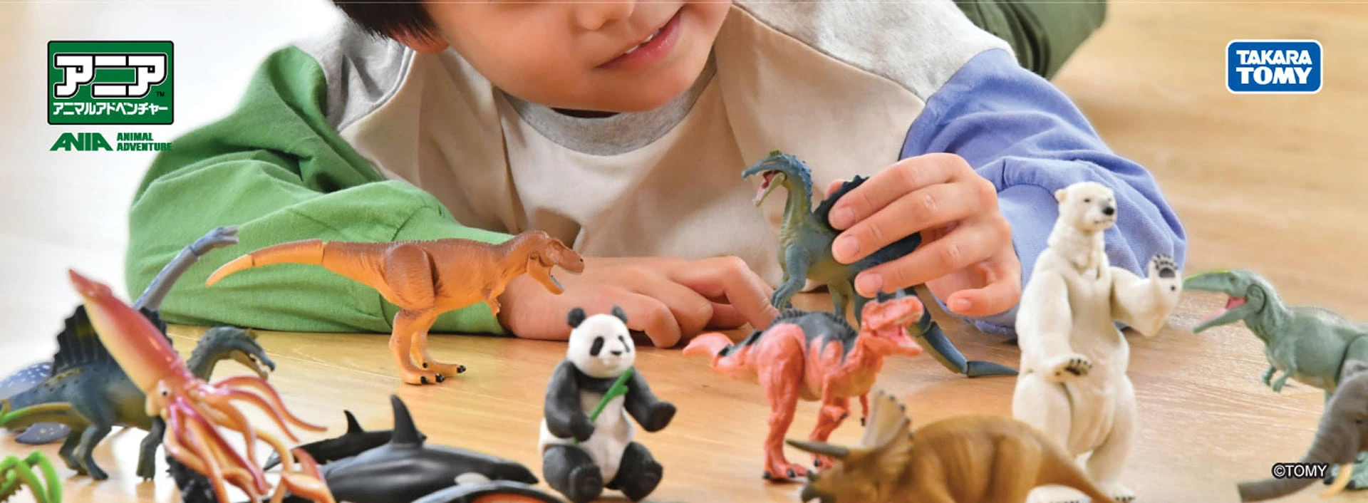 ANIA promotional banner showing a child playing with animal and dinosaur toy figures on a table.