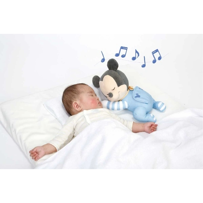  Baby sleeping with a plush Mickey Mouse toy that plays music.