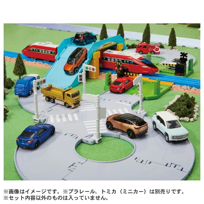  Toy train set with cars on a road, featuring a bridge, train, and various vehicles.
