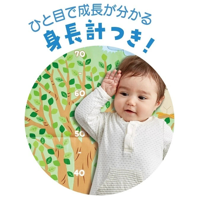  Baby on growth chart blanket with tree design, measuring height.