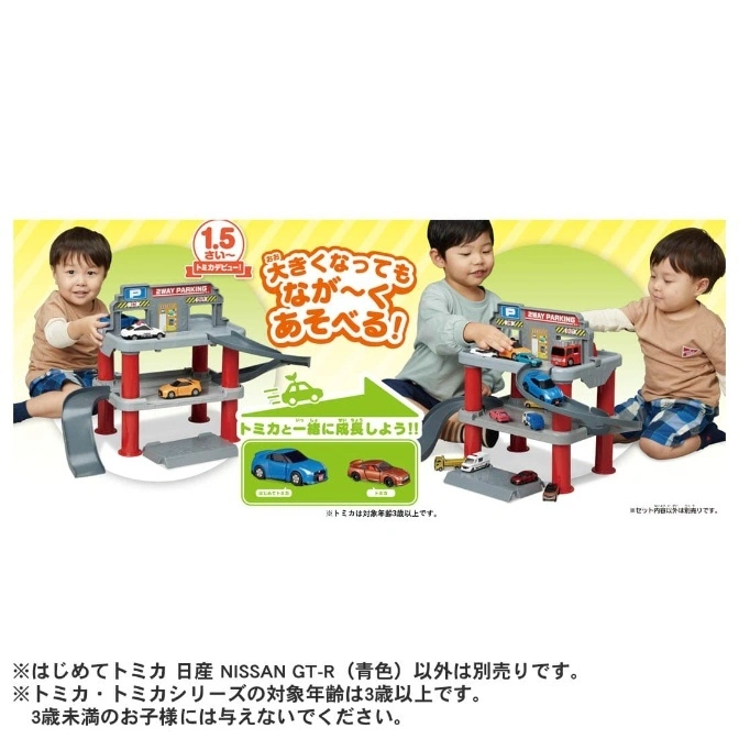  Toy car park playset with two levels, ramps, and toy cars, being played with by two young children.