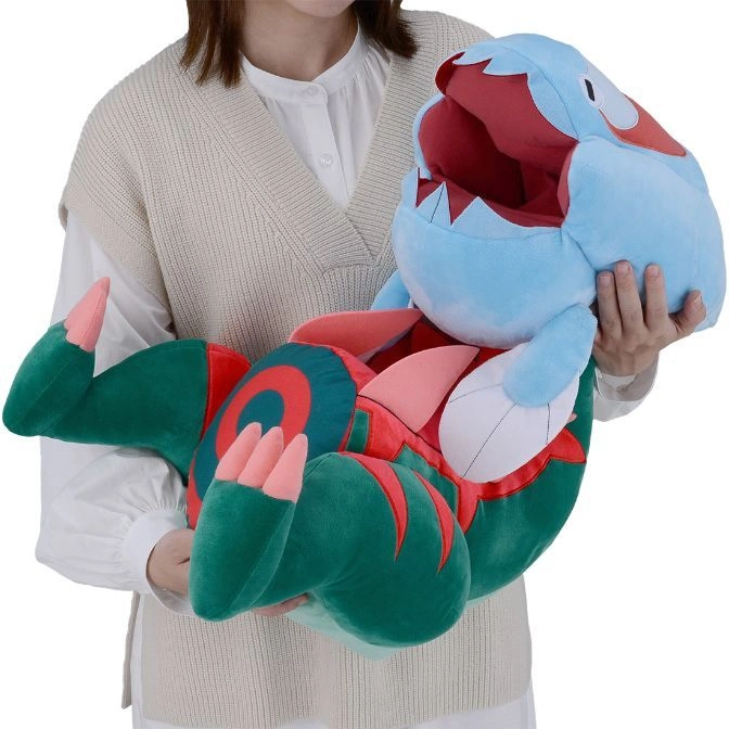  Person holding a plush Trapinch toy with blue head, red mouth, and green body.