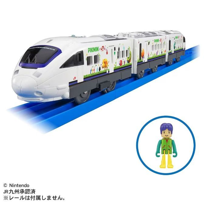 A Pikmin-themed toy train set with a bullet train engine and several passenger cars, displayed on a blue track. A small, stylized figure of a person with blue hair and a green vest stands to the side. The train is white with Pikmin characters and the Pikmin logo printed on the sides.