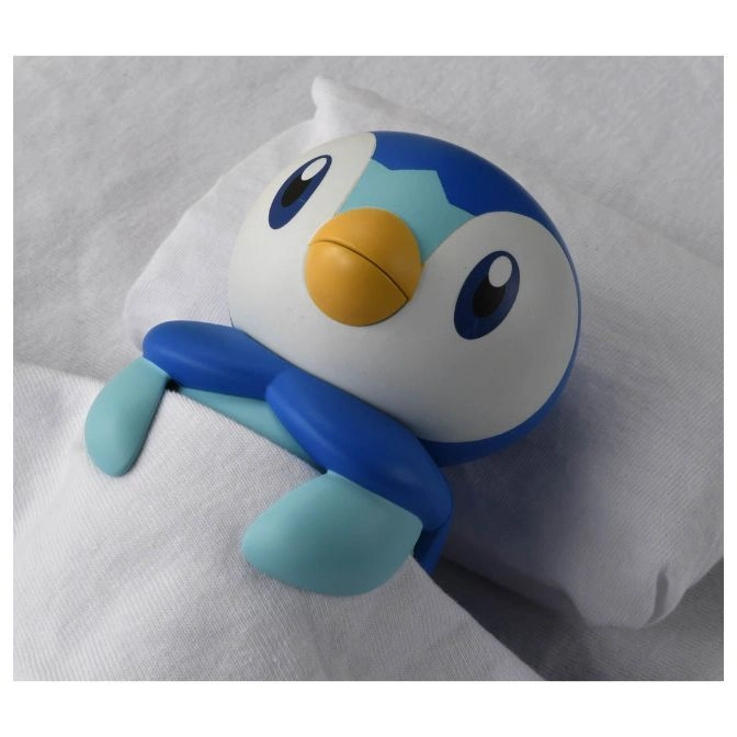  Piplup toy on white fabric. Blue and white penguin-like Pokémon with a yellow beak.