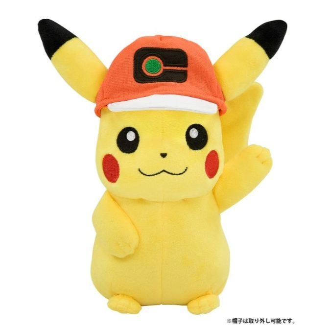 Pikachu plush toy wearing an orange cap with a green and black logo, raising its right arm.
