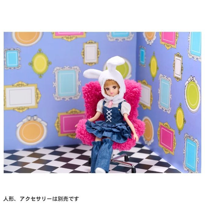  Doll in bunny hat sits in pink chair. Denim dress and boots. Whimsical framed wallpaper.