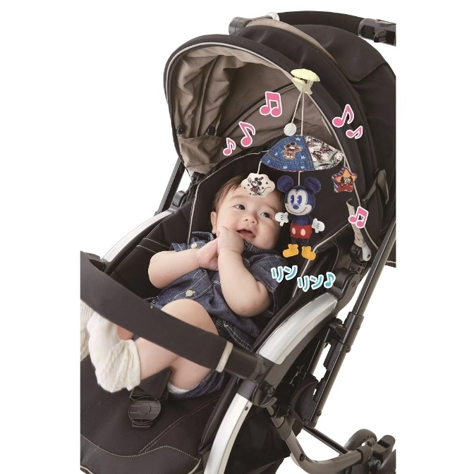 Baby in stroller with Mickey Mouse mobile toy hanging above.