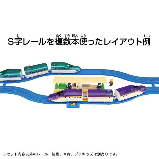  A toy train set with two trains, a station, and a figure on a blue track.