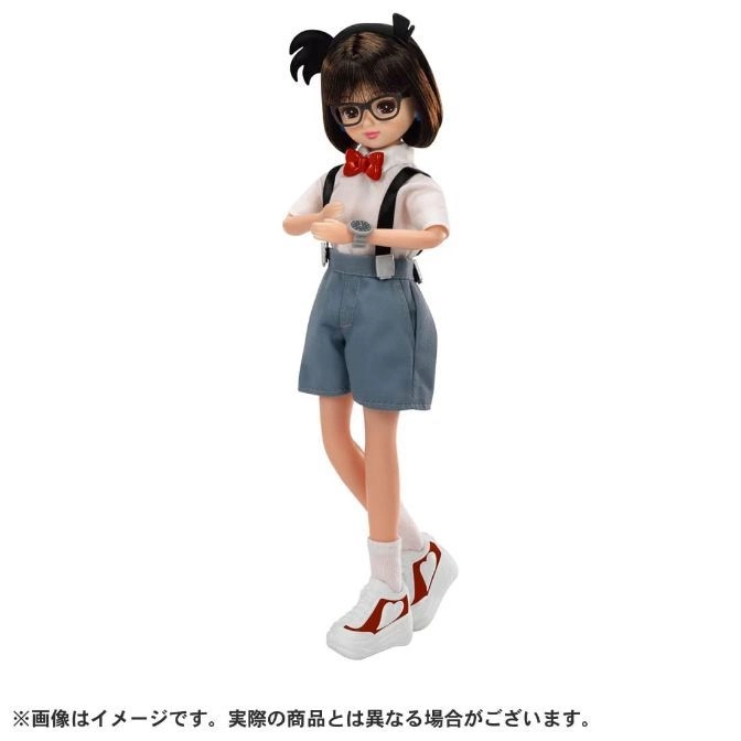  Doll of girl in shorts, suspenders, bow tie, glasses, and sneakers, standing with arms crossed.